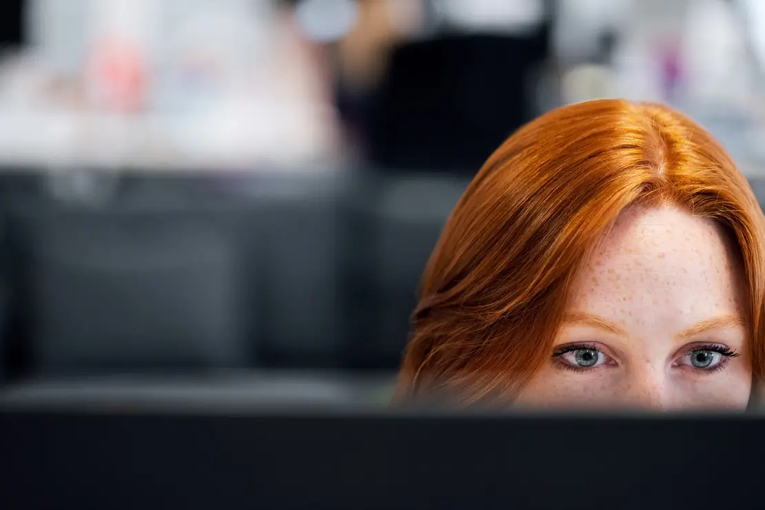 Photograph of red headed waste management customer service woman working at a computer.