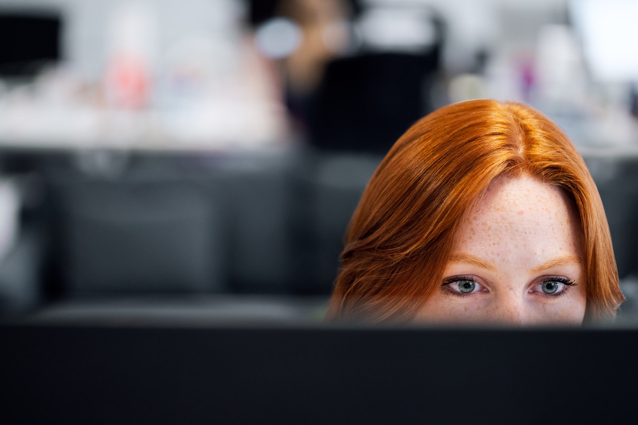 Photograph of red headed woman working at a computer