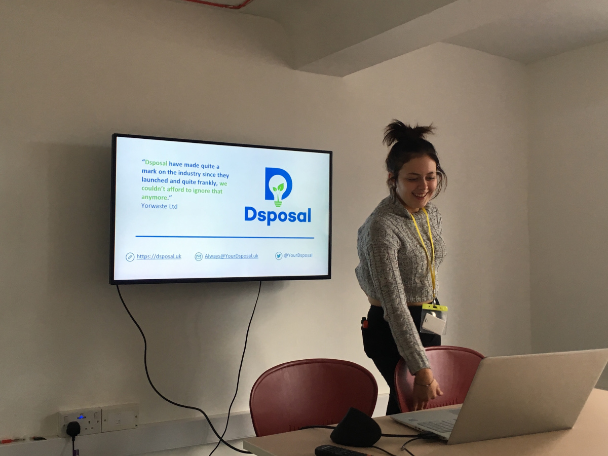 Girl, Cherry Passmore, giving a presenation in a small white room with Dsposal logo